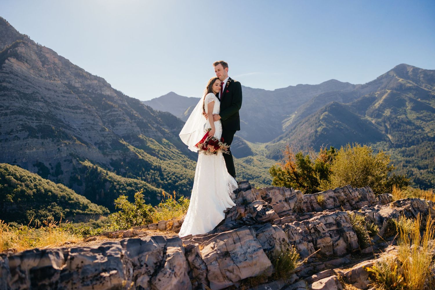 Couple holding each other during a wedding photoshoot on a rocky overlook in the mountains of Utah