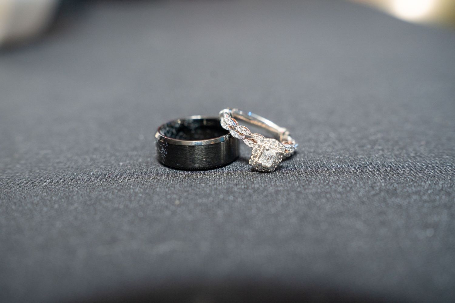 Wedding rings photographed on a dark textured surface with dramatic lighting.