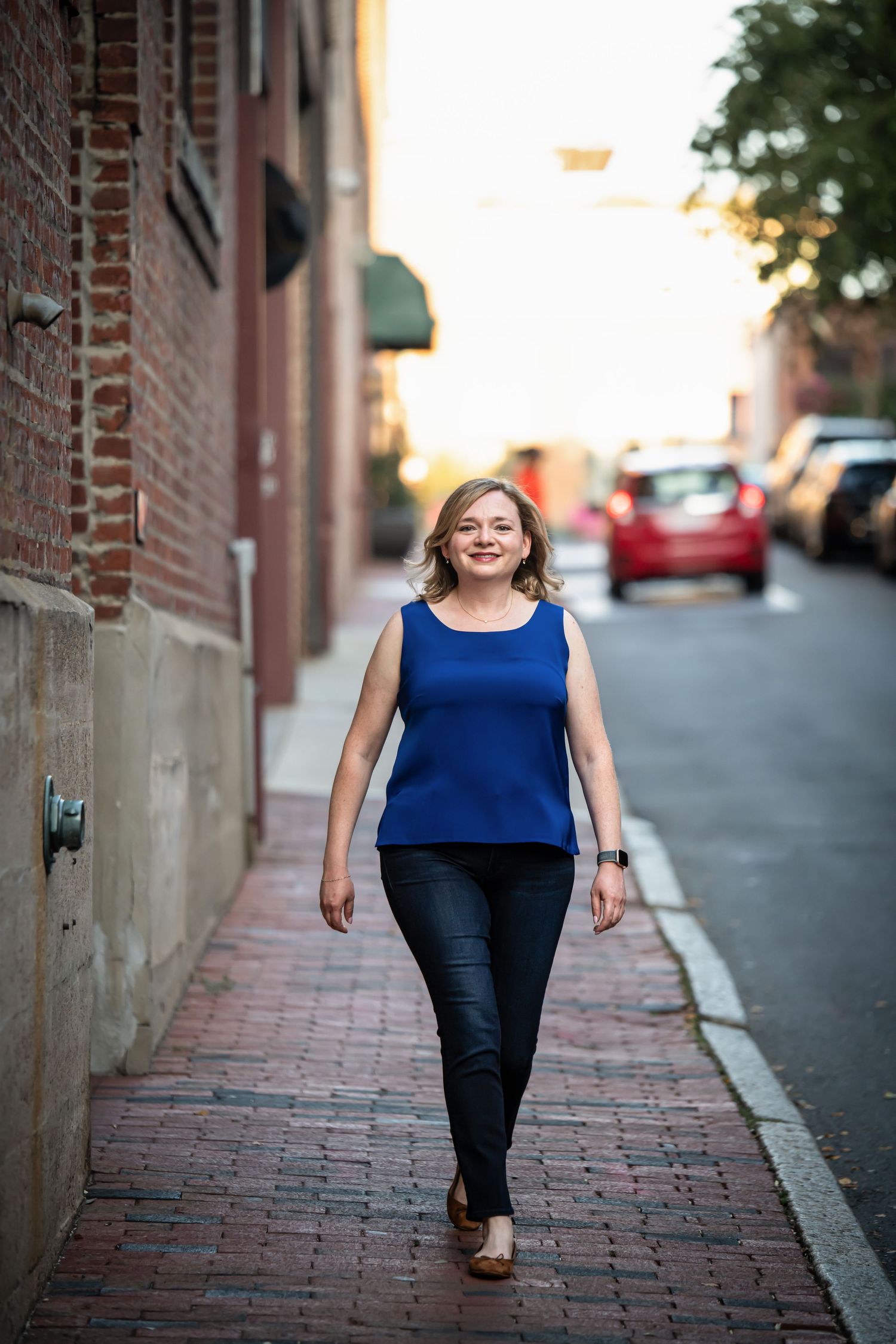 Urban portrait series on brick sidewalk featuring royal blue top and dark pants.