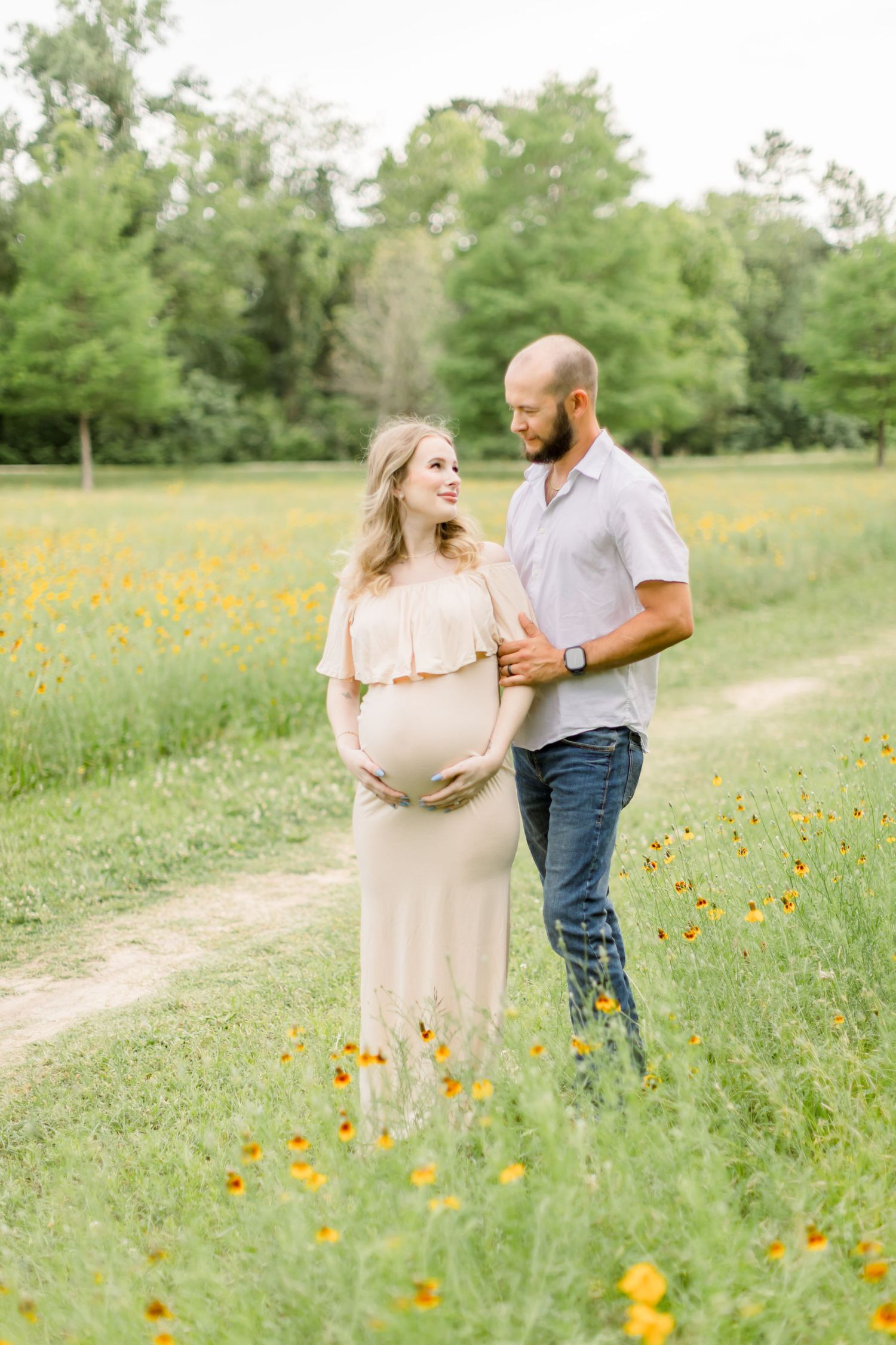 A maternity photoshoot in a wildflower field captures a couple's joy during golden hour.