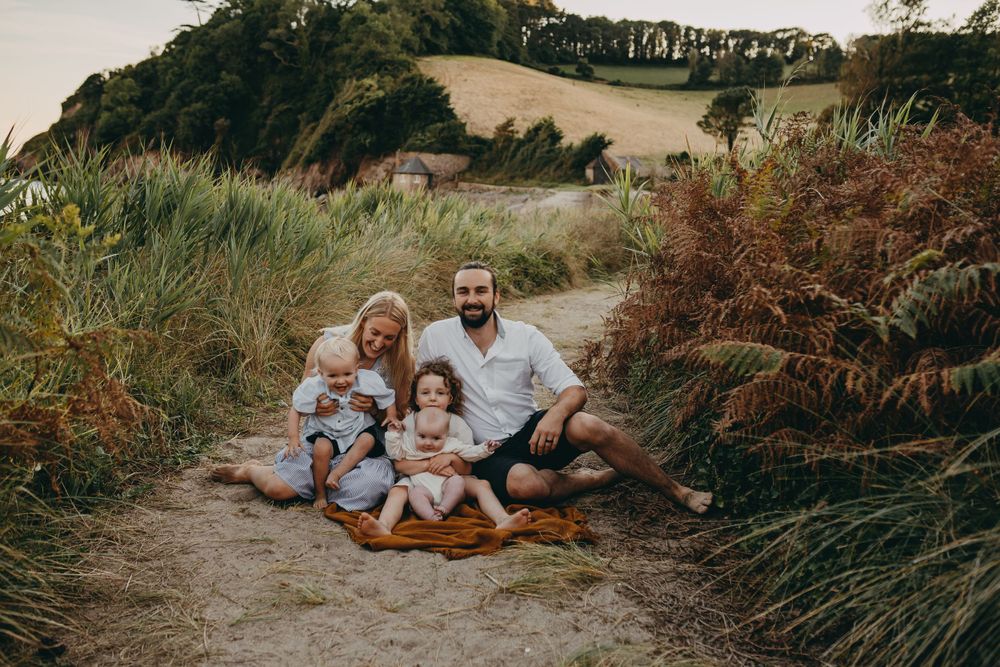 A family sits together on a path surrounded by tall grass during golden hour at sunset.