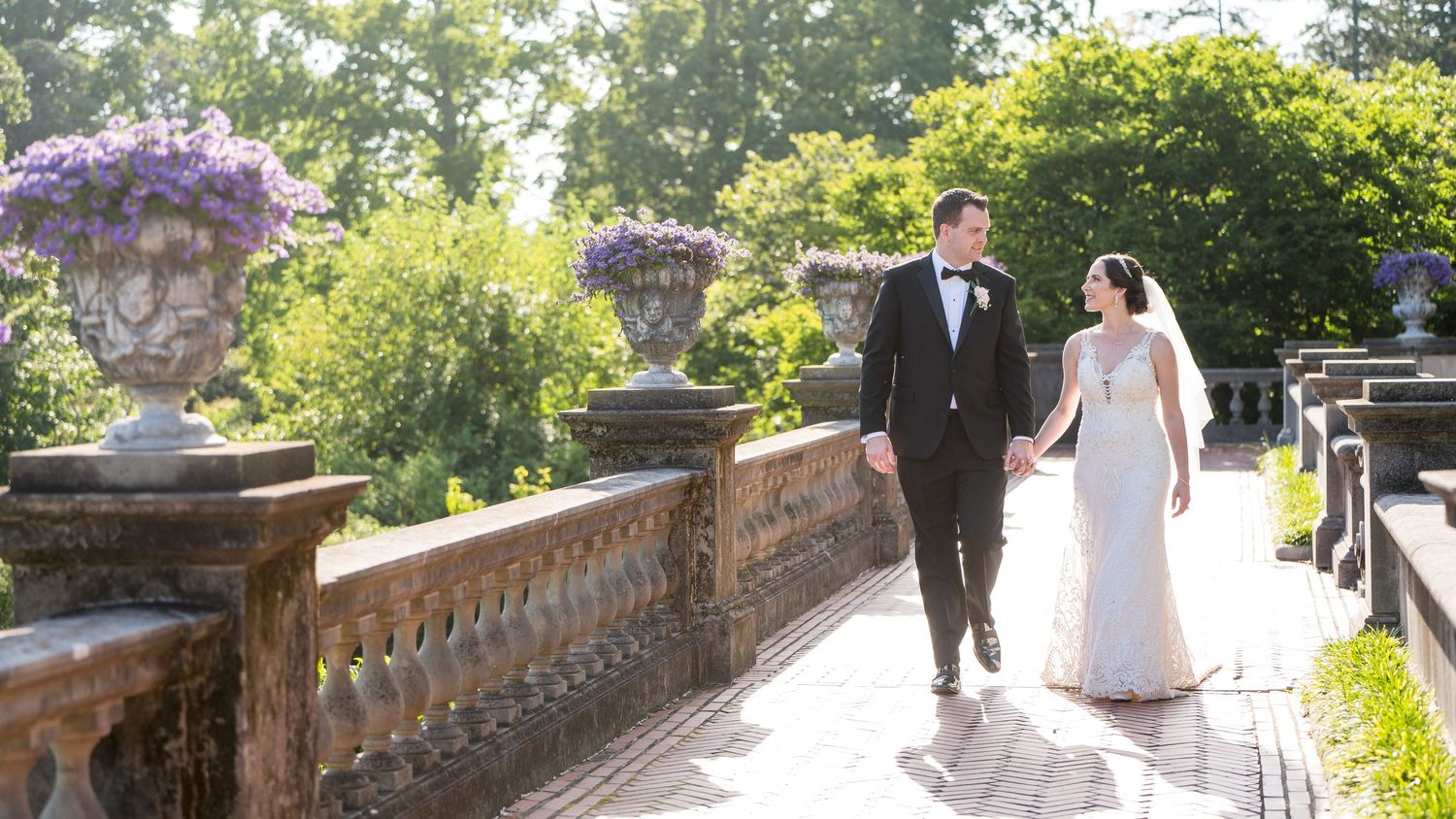 Couple walking hand in hand through the gardens of Westbury Gardens.