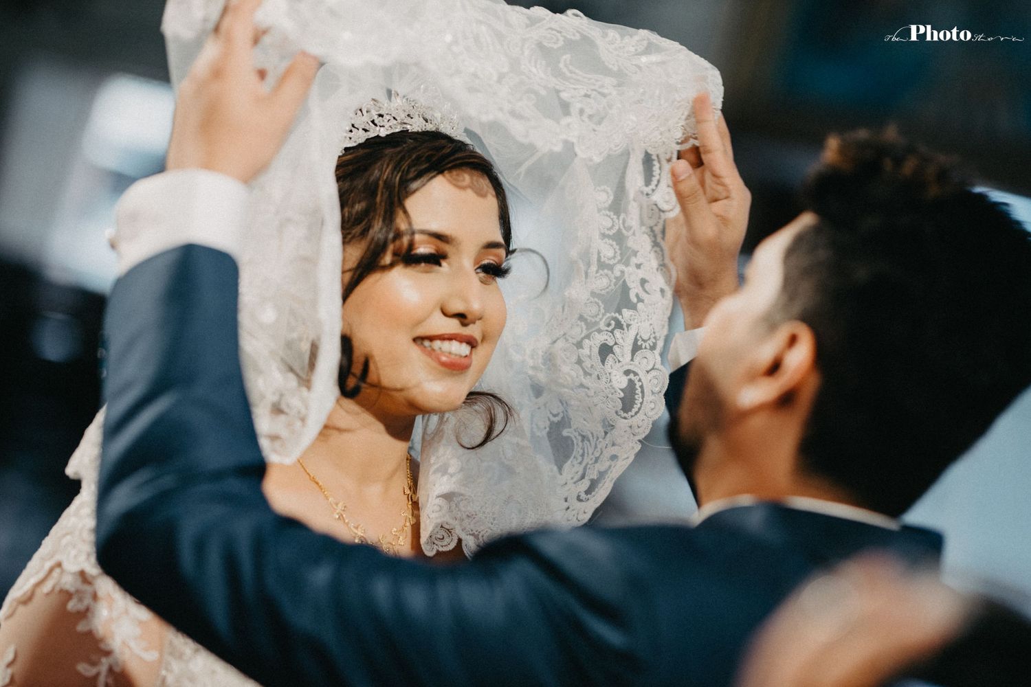 Emotional moment during a wedding ceremony with bride in lace veil and groom in navy suit.
