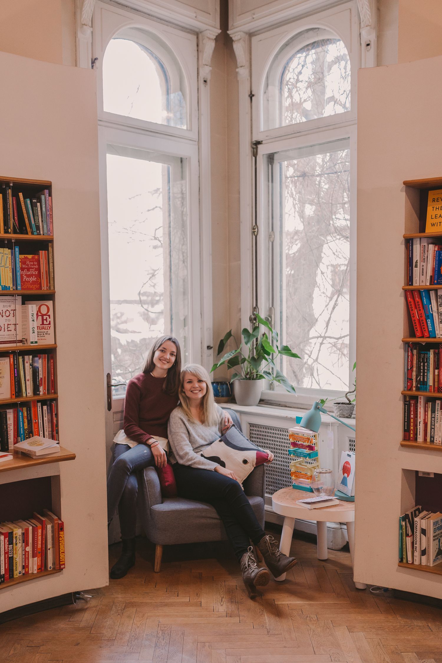 A cozy library corner with arched windows, bookshelves, and comfortable seating for reading.