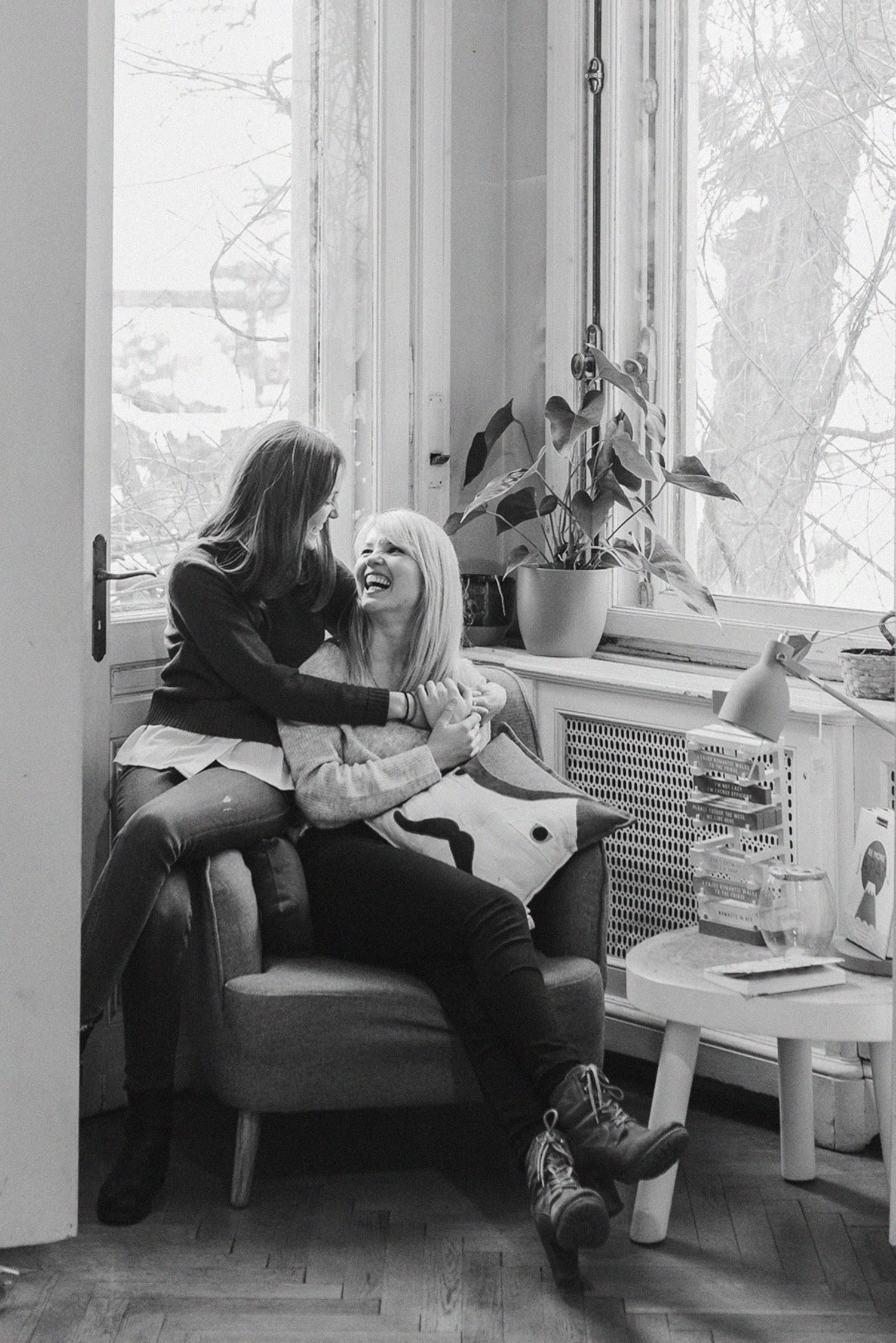 Two people relaxing on cushioned seating by a bright window in a library.
