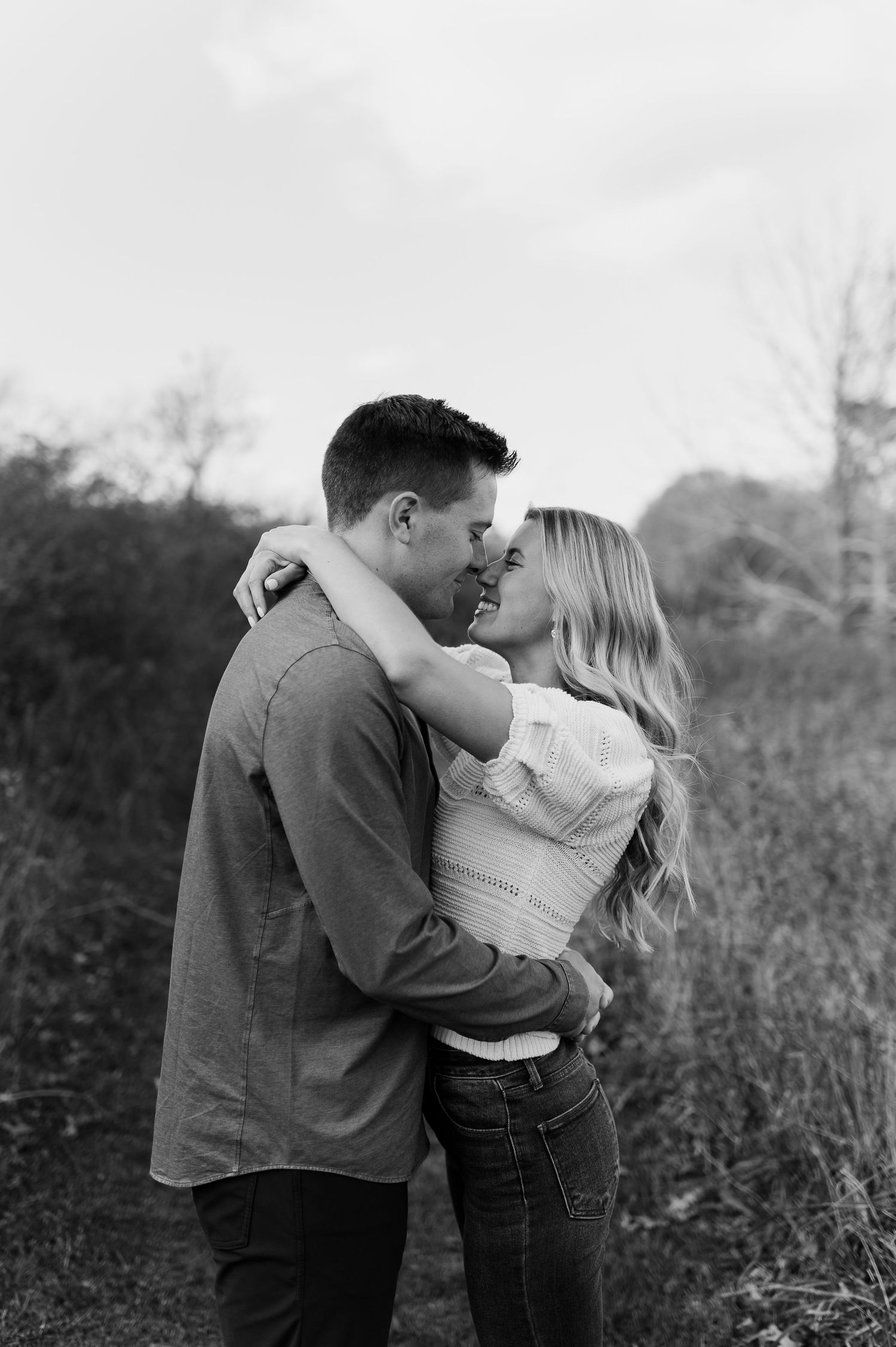 Intimate black and white portrait of a couple sharing a tender moment outdoors.