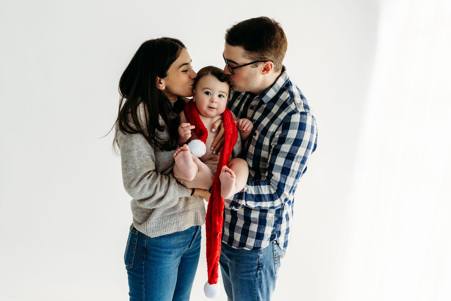 Family in casual wear sharing intimate moment against white studio background.