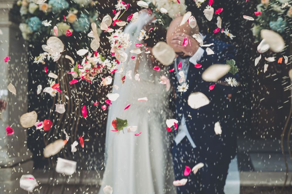 Newlywed couple showered with colorful rose petal confetti outside the church.