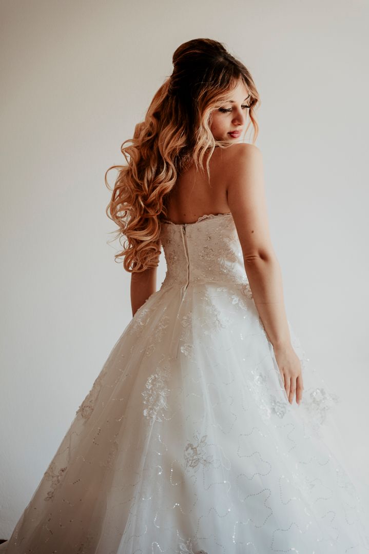 A wedding dress with delicate lace details and full tulle skirt shown from behind.
