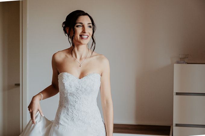 A strapless lace wedding gown is showcased in a bright, minimalist getting-ready room.