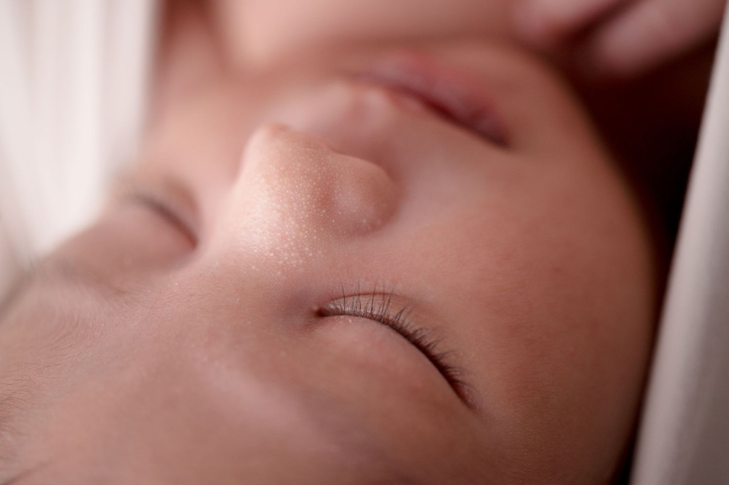 Peaceful sleeping newborn details in gentle lighting and neutral tones.