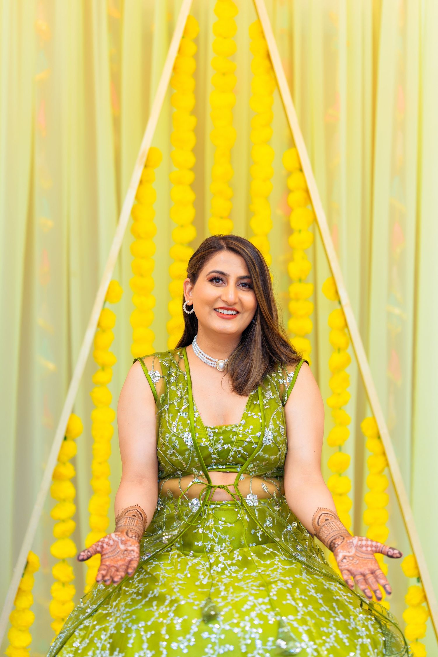 Festive wedding attire featuring emerald green lehenga with detailed embroidery against yellow decor.