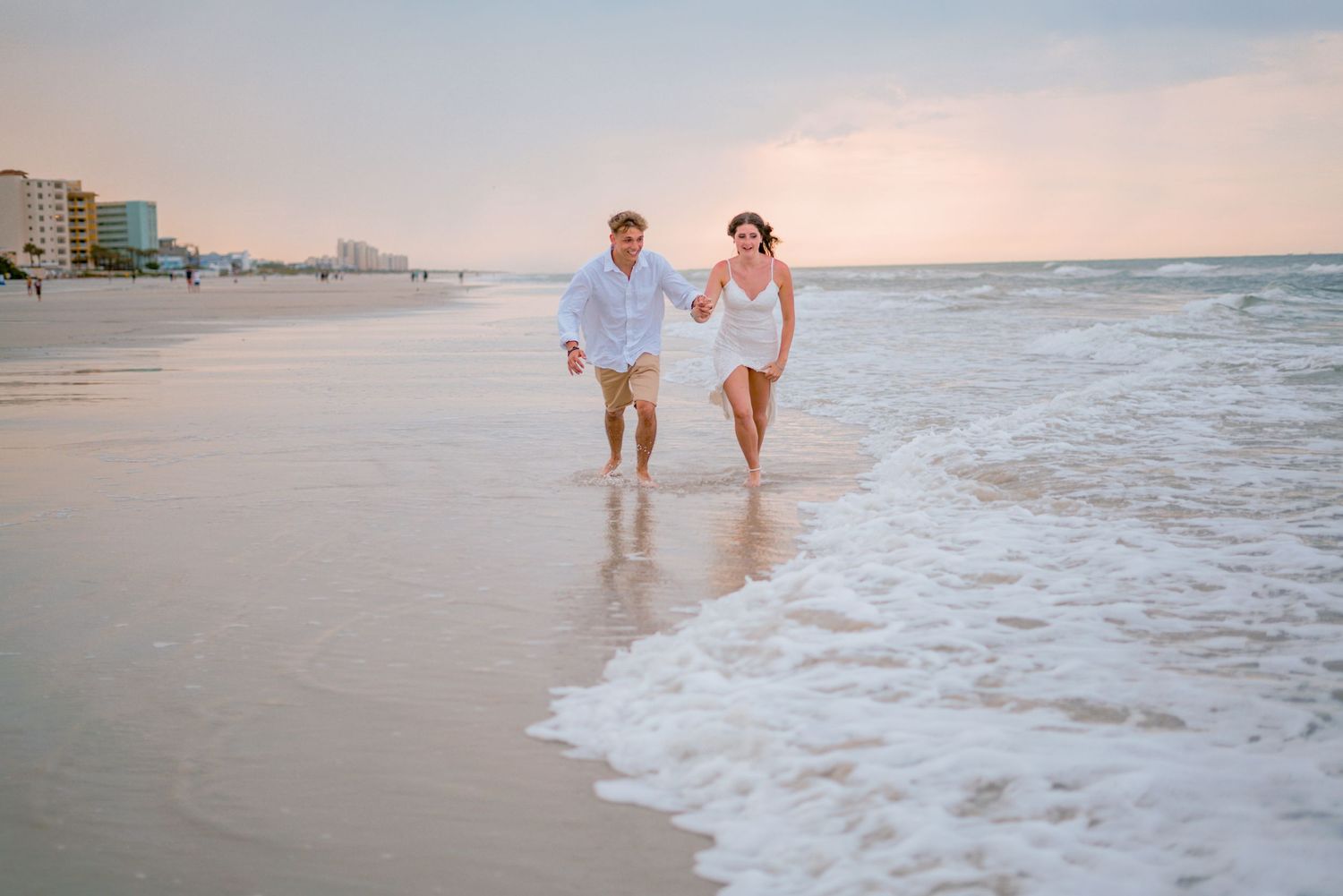 beautiful, well edited image of a couple running along the beach at sunset