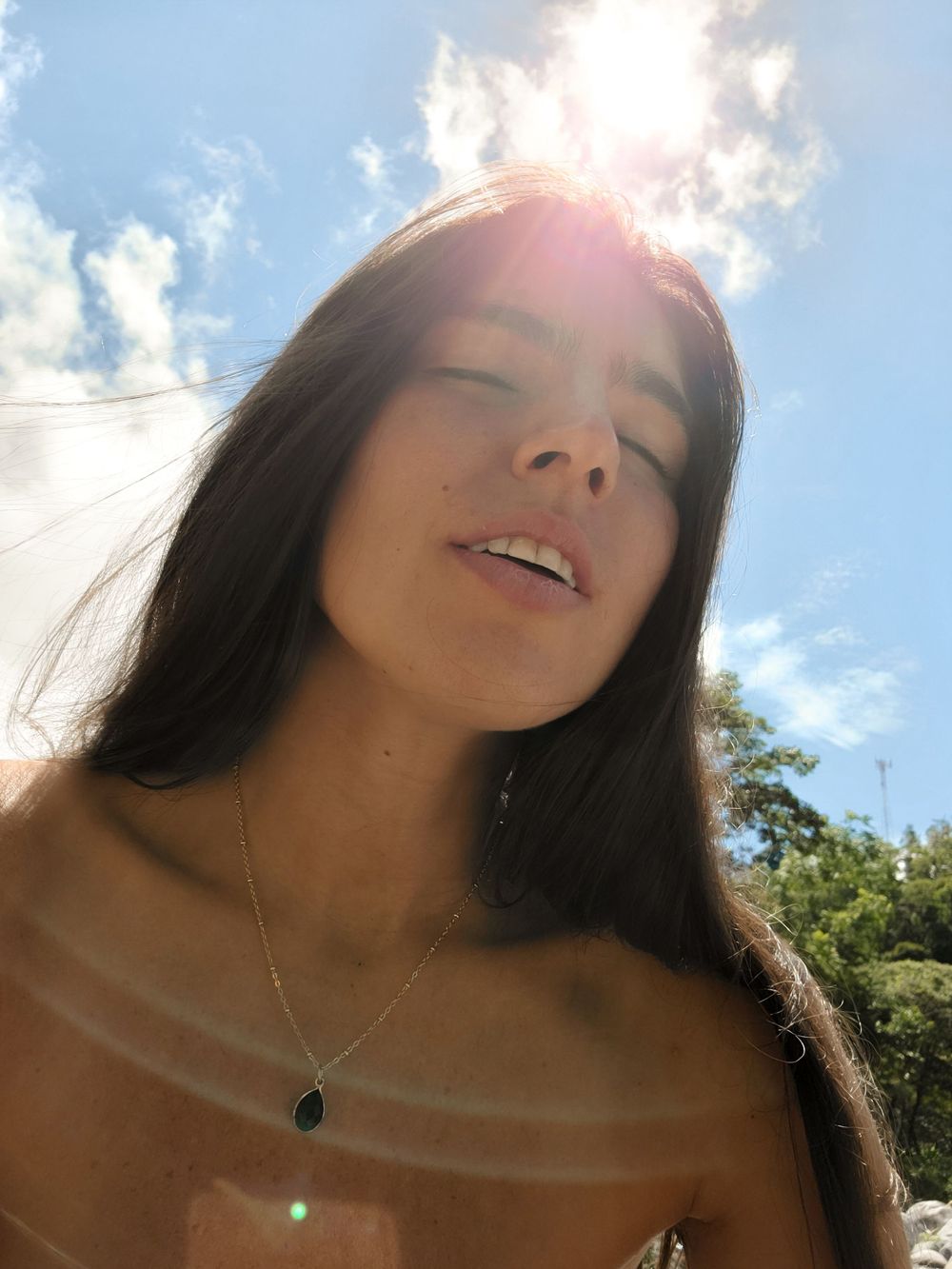 Sunlit summer portrait against blue sky with lens flare effect.