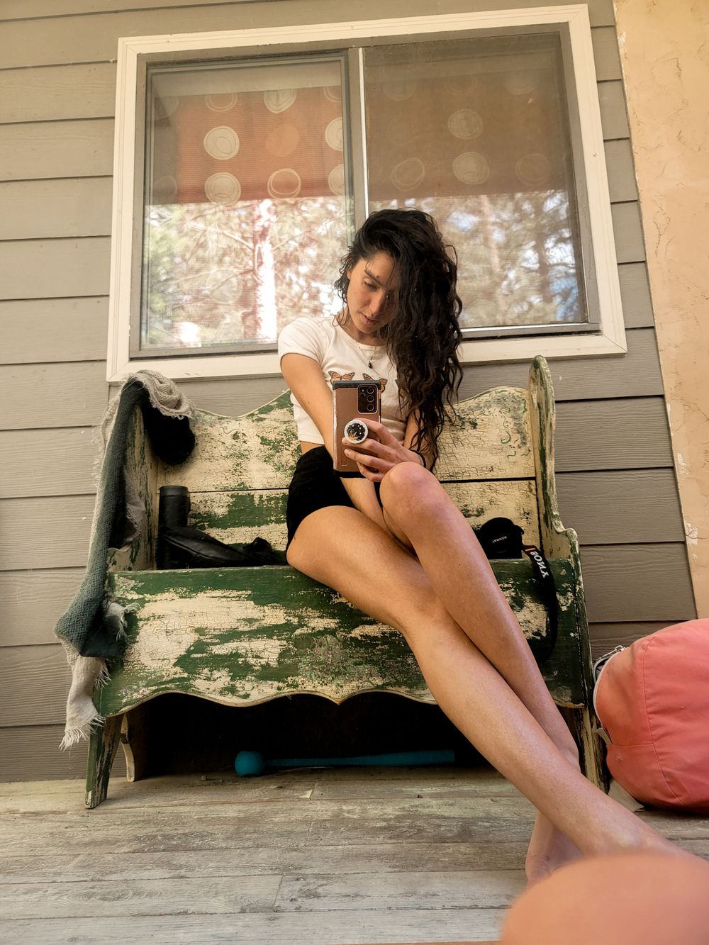 Casual outdoor portrait of someone relaxing on a weathered wooden bench on a porch.
