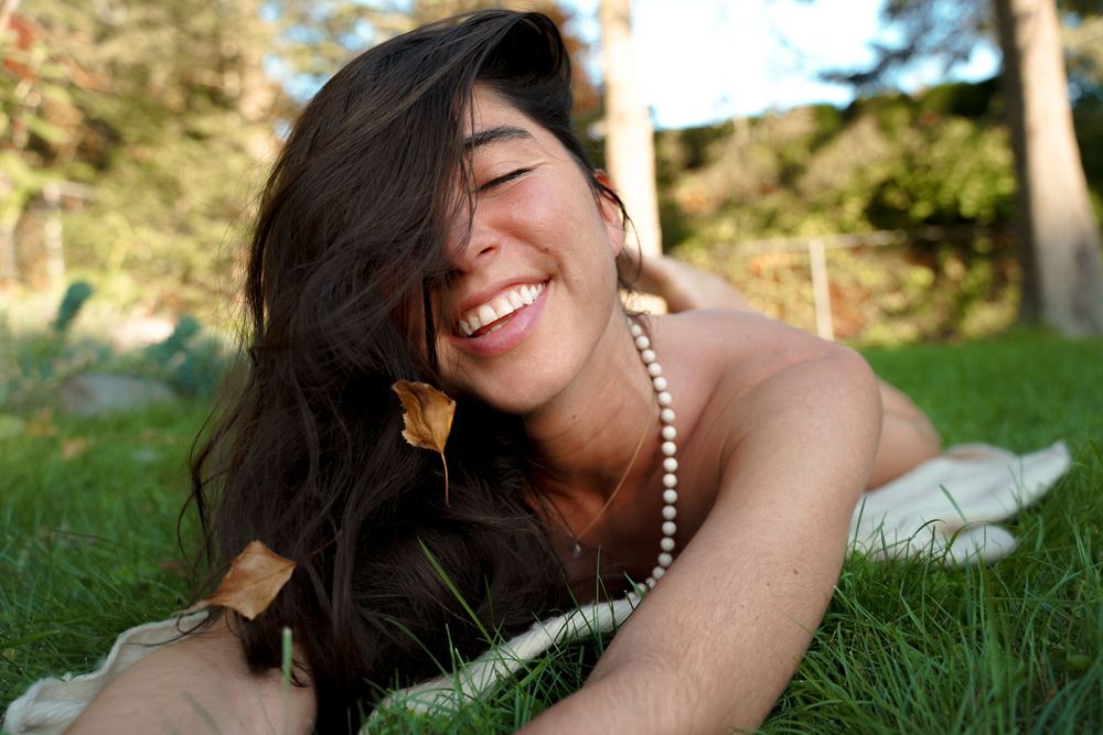 A joyful moment captured outdoors on grass with pearl necklace and natural sunlight.