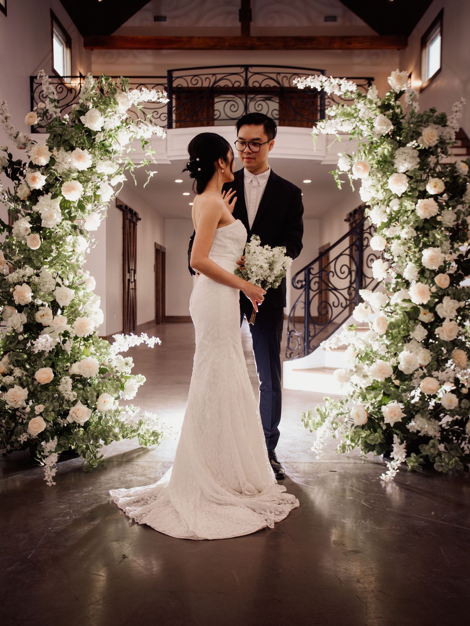 Wedding at Primrose Hill with ivory dress, sage colored flowers and arches, and groom in royal blue suit.
