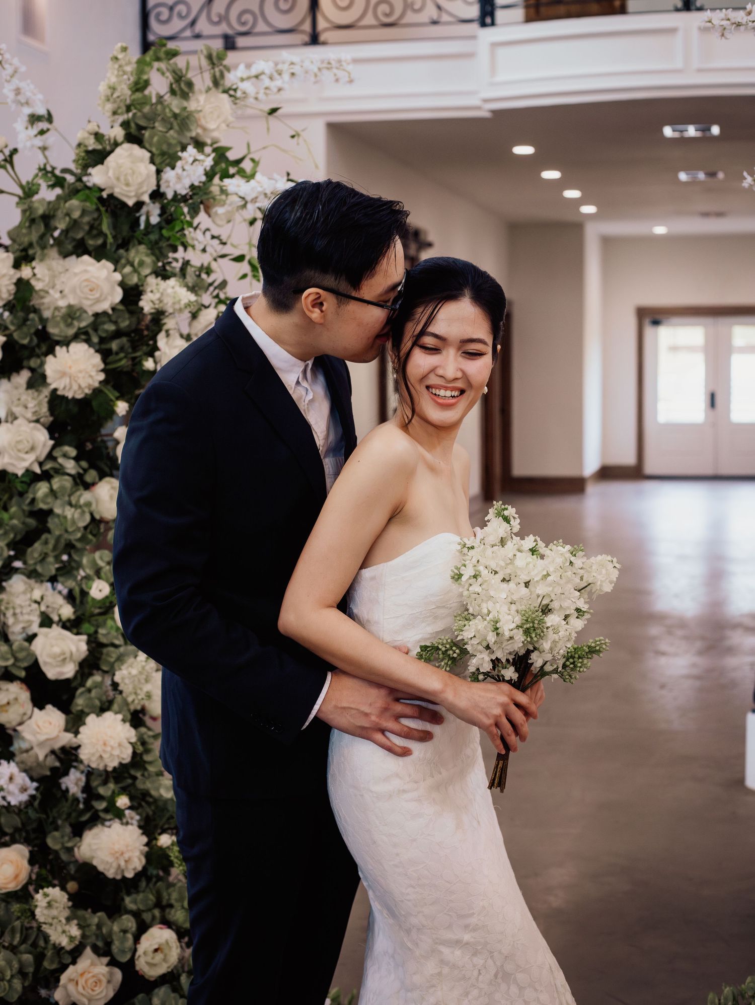 Wedding at Primrose Hill with ivory dress, sage colored flowers and arches, and groom in royal blue suit.