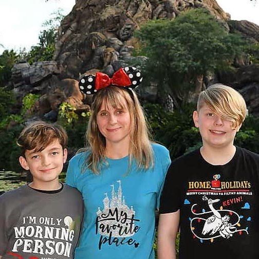 Three people wearing themed t-shirts and Mickey ears at a Disney park.