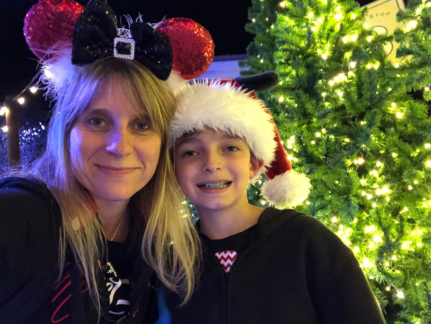 Festive holiday photo with illuminated Christmas tree and sparkling Minnie Mouse ears.