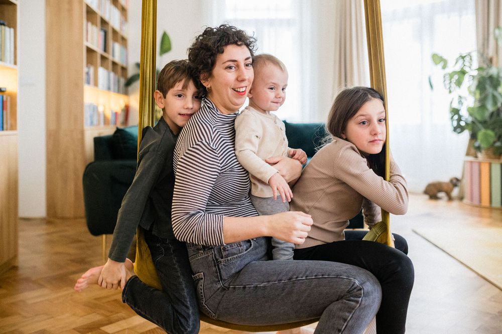 Group sitting together on an indoor swing in a bright minimalist living room.