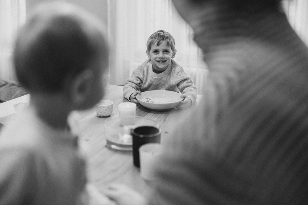 A black and white photo showing family mealtime around a table with joyful expressions.