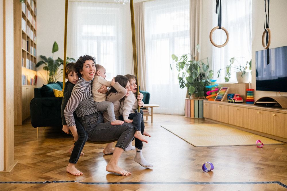 Active family moment in bright living room with wooden floors and indoor plants.