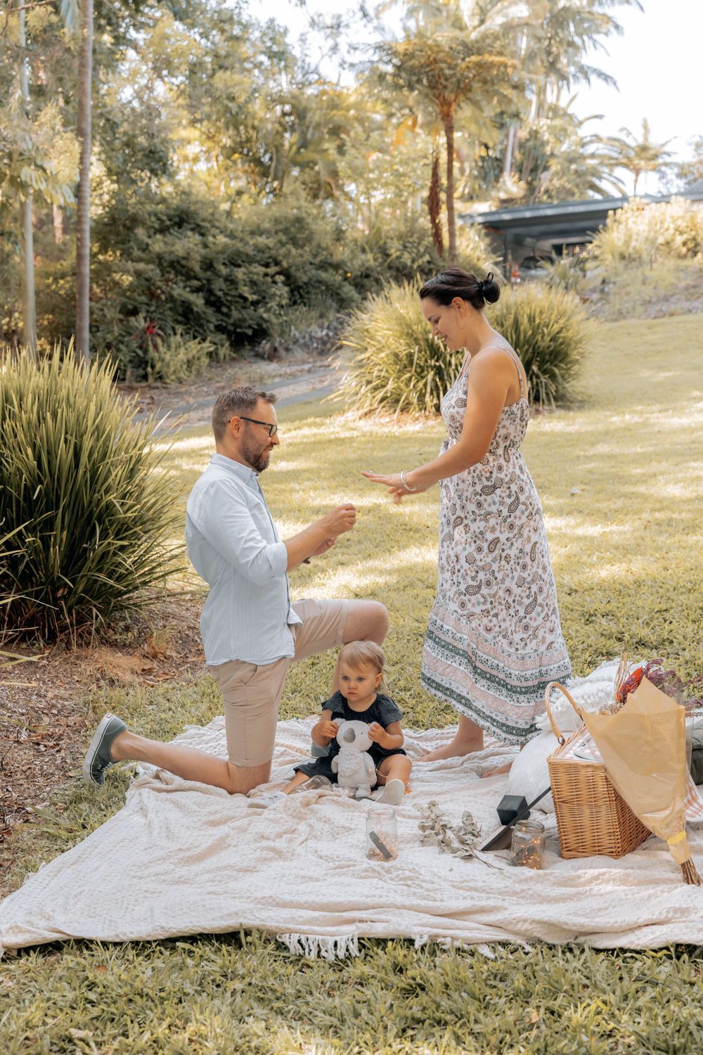 A picturesque proposal moment unfolds during an outdoor picnic with a blanket and basket.