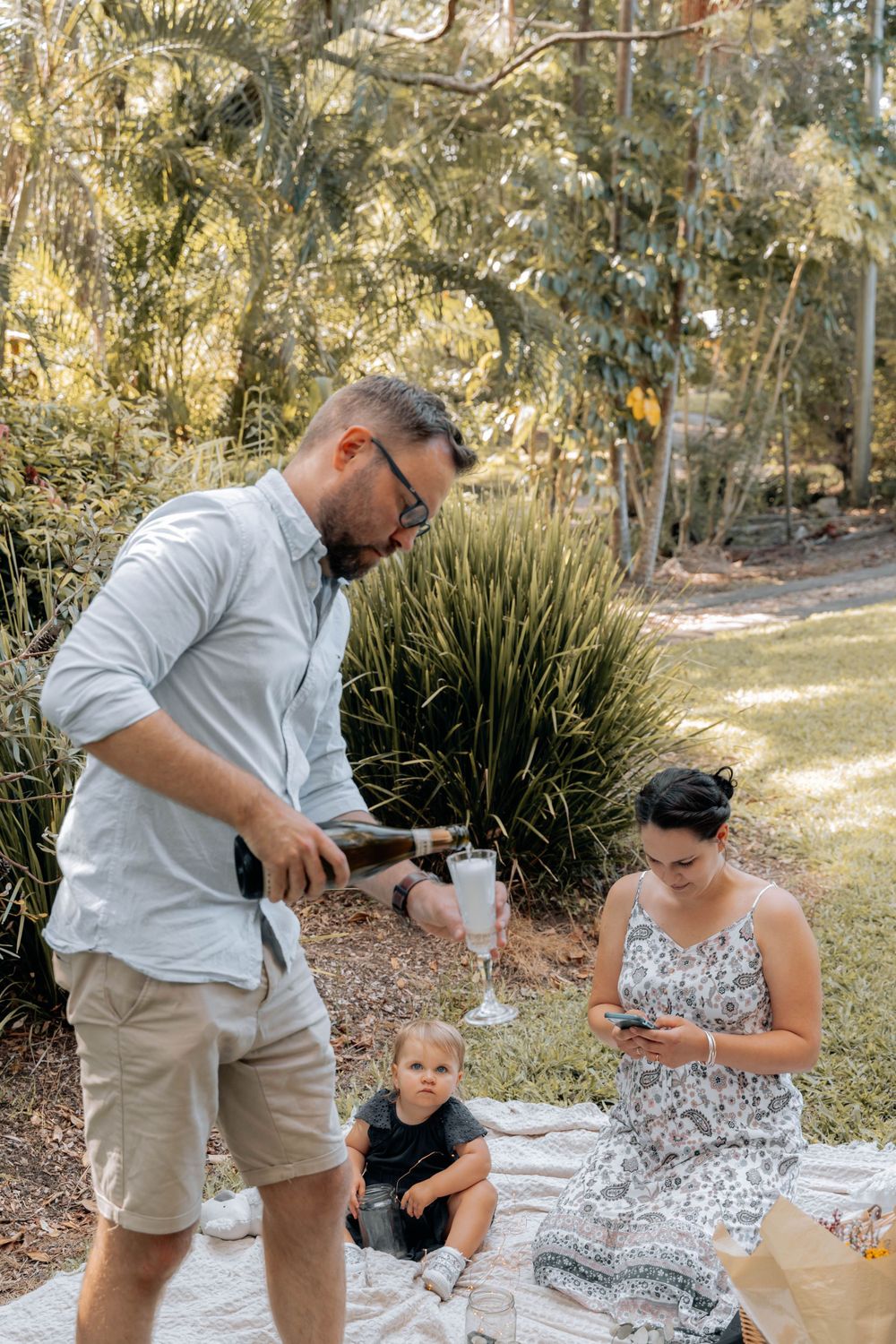 A family shares drinks and snacks during their garden picnic celebration.
