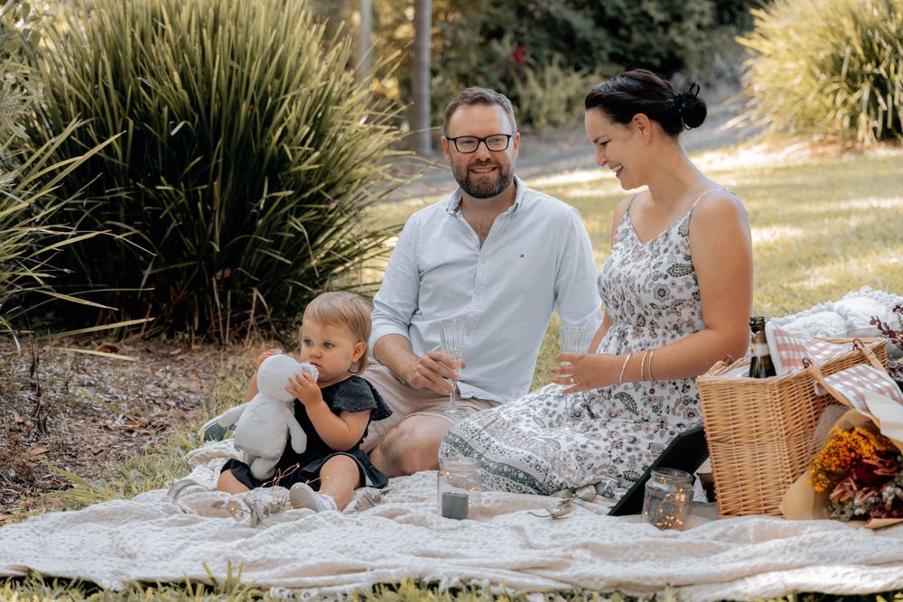 A casual family gathering on a picnic blanket surrounded by lush garden landscaping.