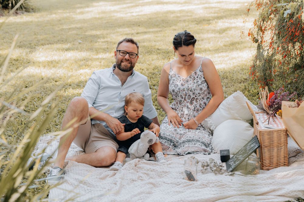 A candid family moment during a garden picnic with wicker basket and blanket.