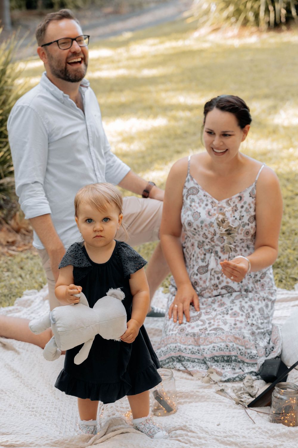 A joyful moment shared during a family picnic on a white blanket outdoors.