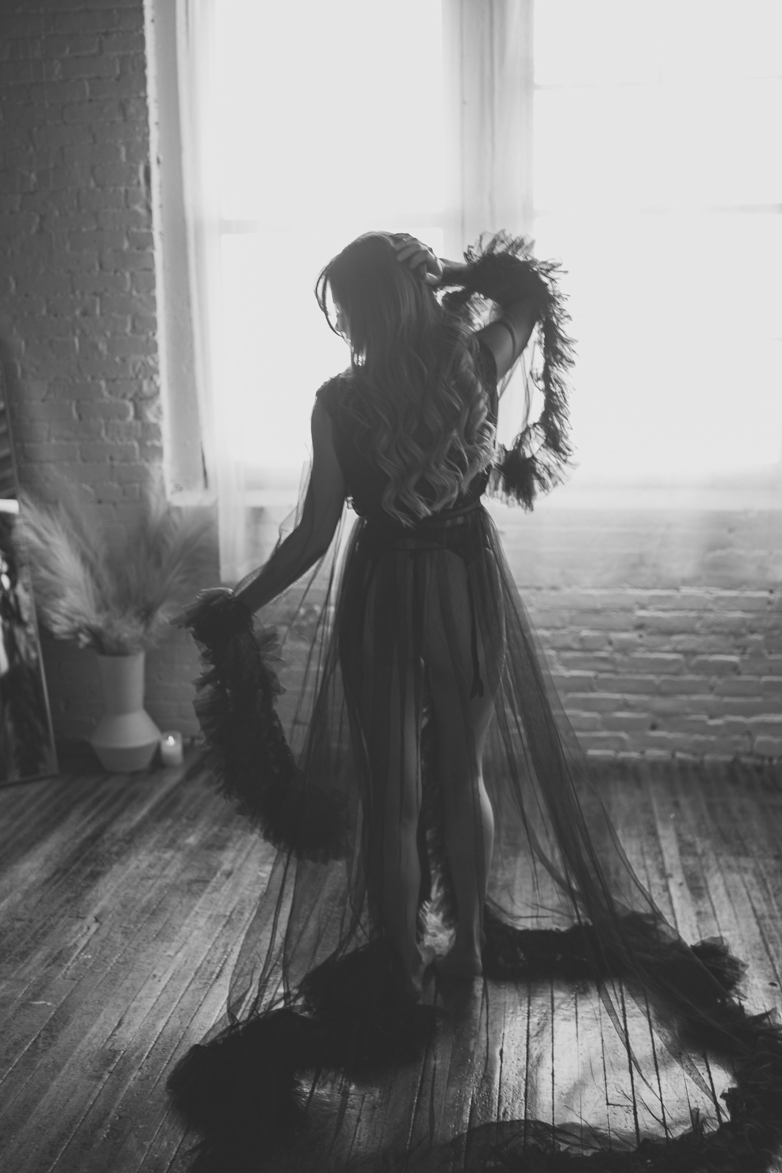 Dramatic silhouette in flowing black gown against window light.