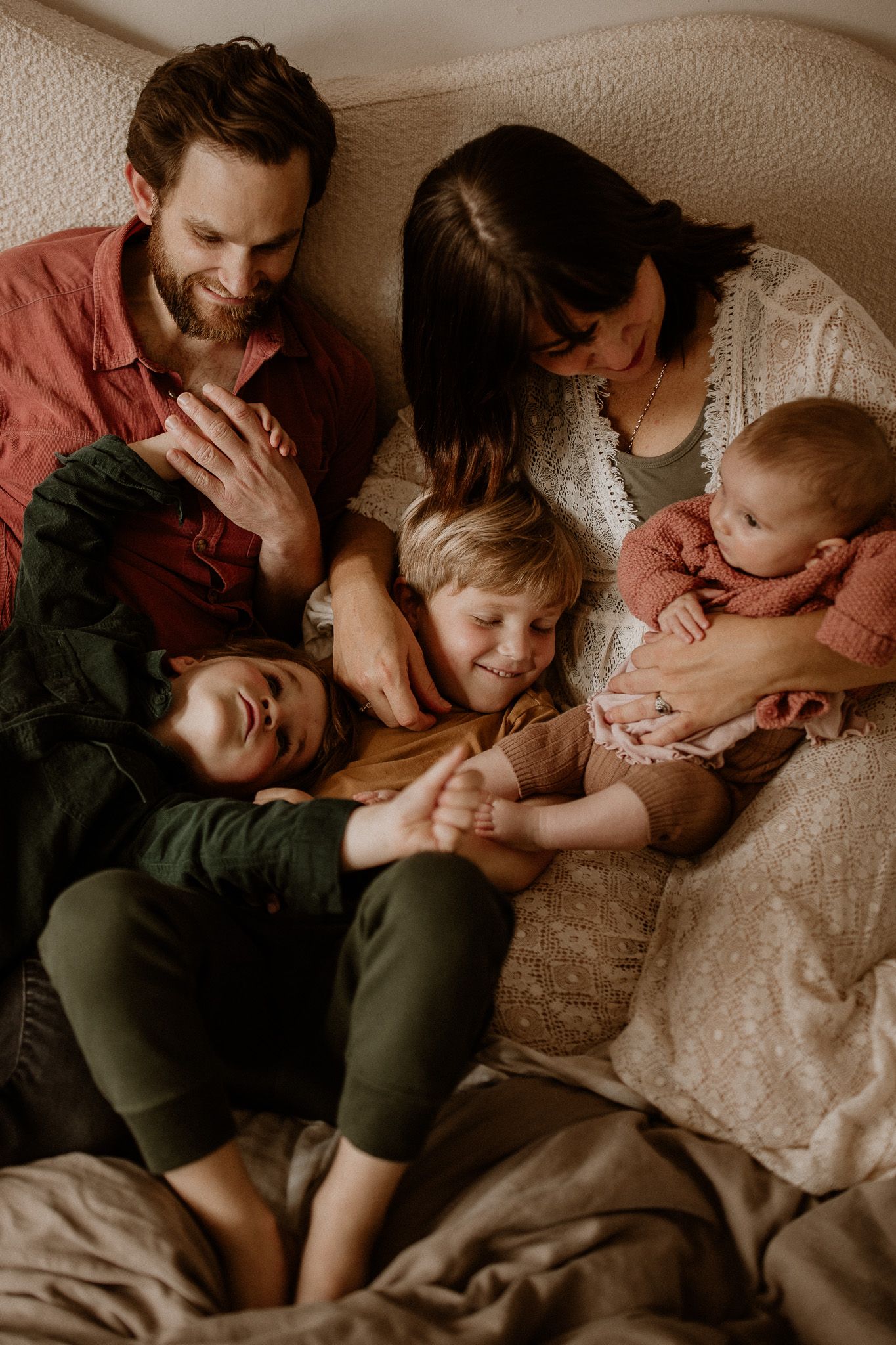 A family shares an intimate moment of laughter and cuddles on their couch.