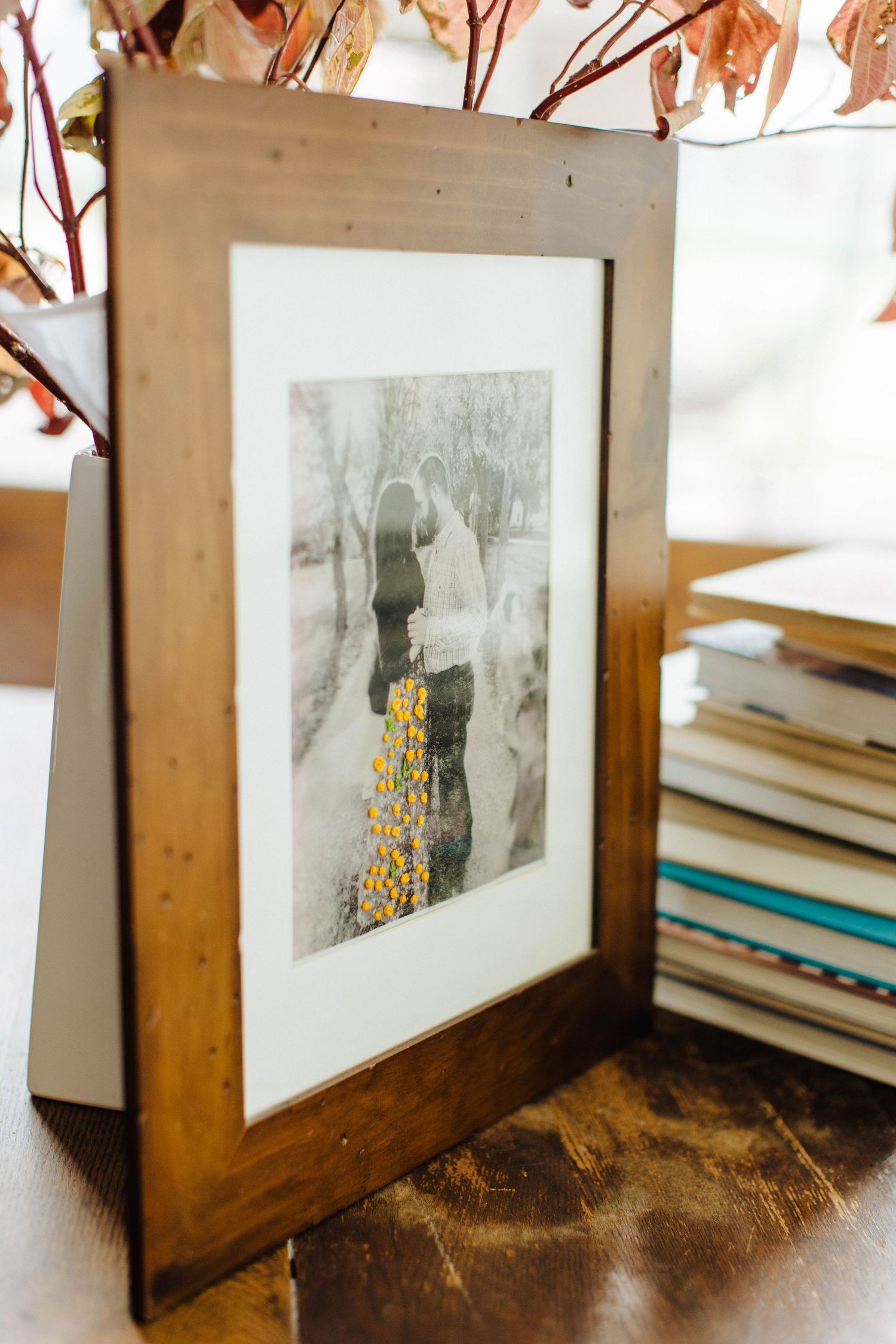 Wooden framed black and white photographs with yellow embroidered details on display.