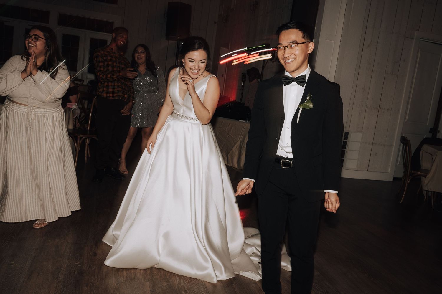 A joyful wedding reception moment captured on the dance floor with guests looking on.