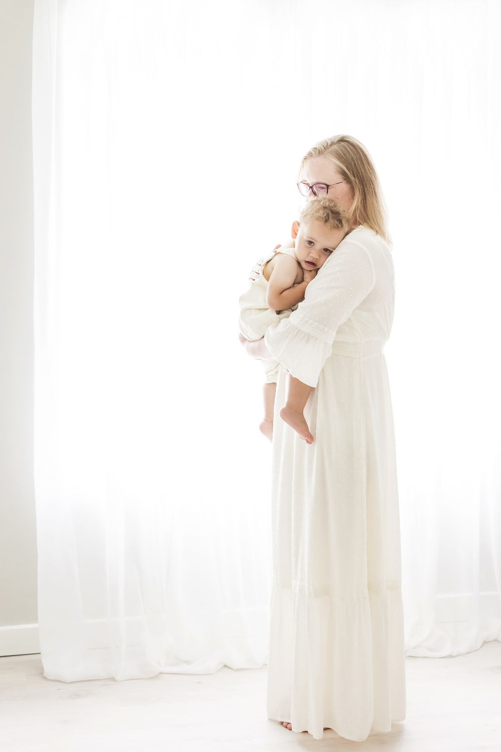 full length image of mother holding baby close backlit light and airy