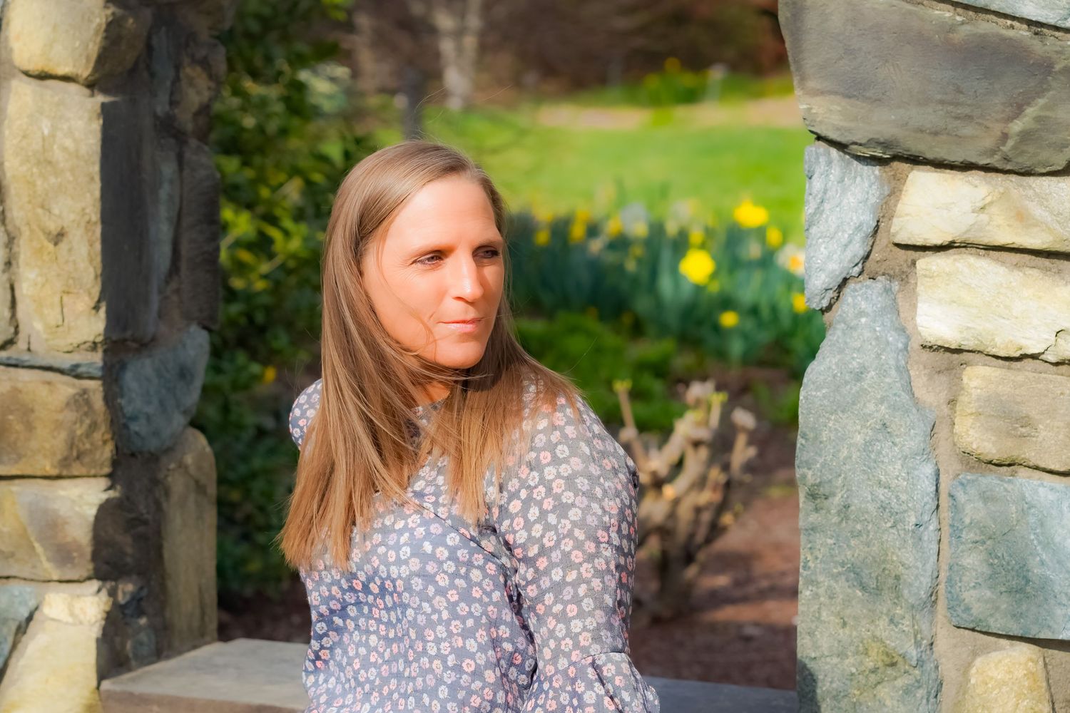 A scenic portrait taken between stone pillars with daffodils in the background.