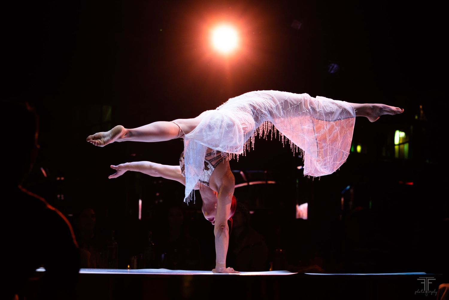 Dramatic silhouette of a dancer performing a balance pose under stage lighting.