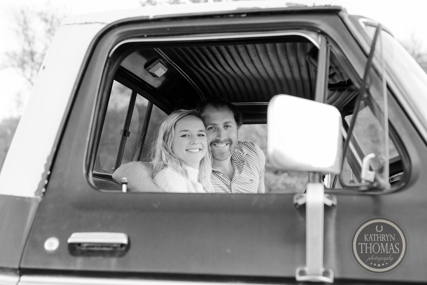 Black and white photo of a couple sharing a moment inside a vintage truck cab.