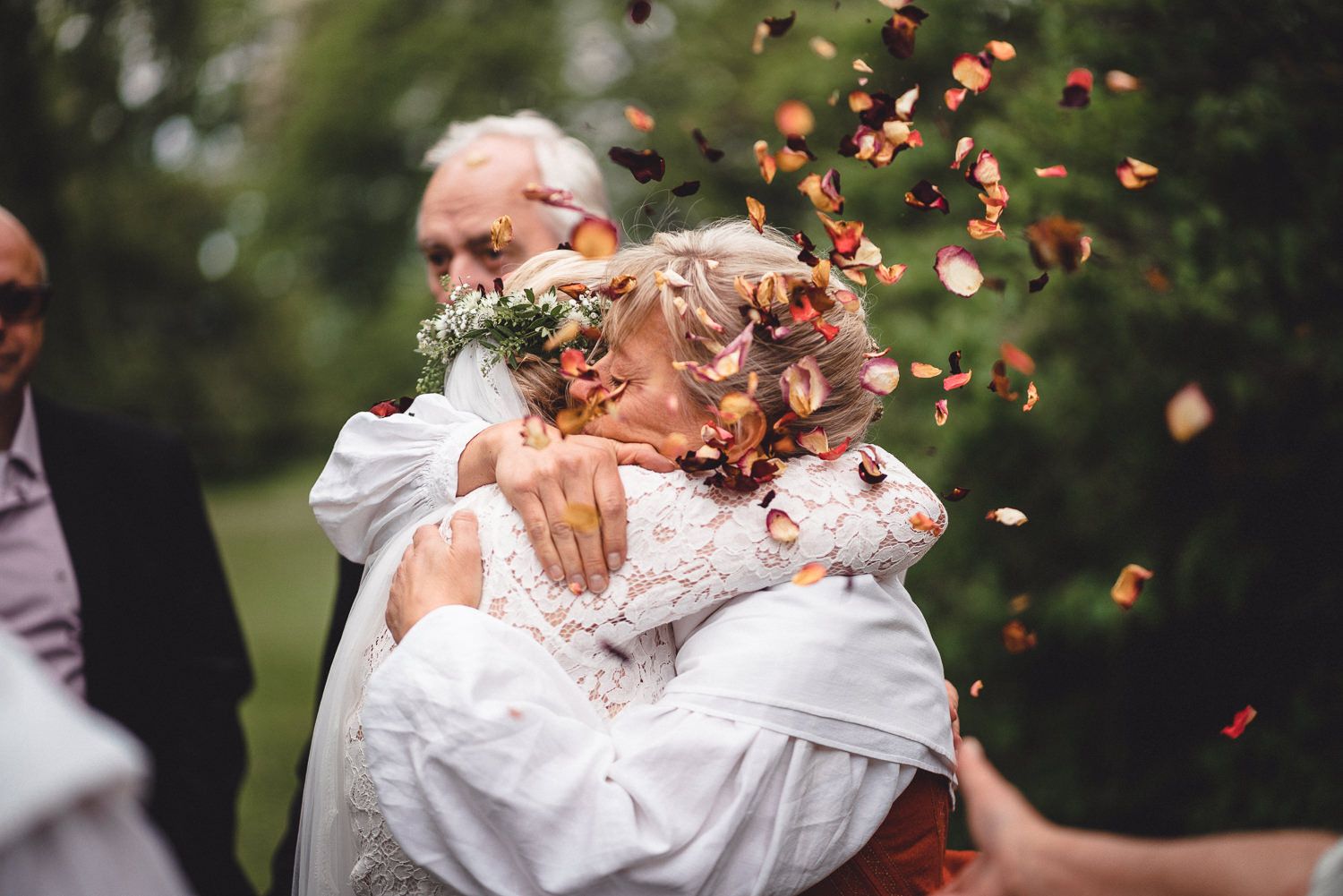 Brud kramar sin mamma efter vigseln med blomblad som kastas i luften runtomkring dem på Kinnekulle