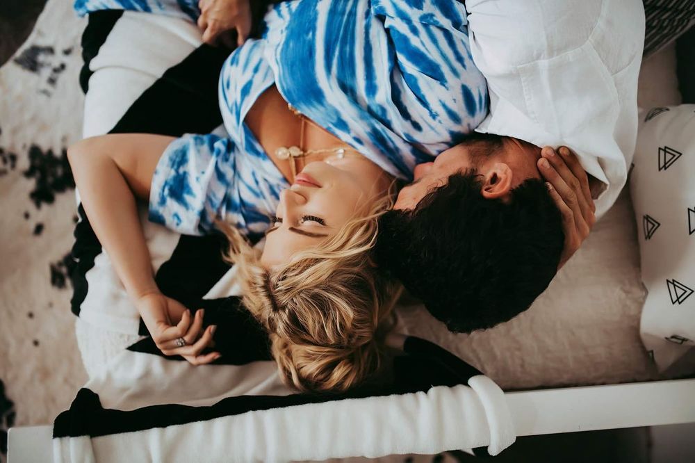 Friends lie side by side on the ground wearing matching blue and white tie-dye outfits.