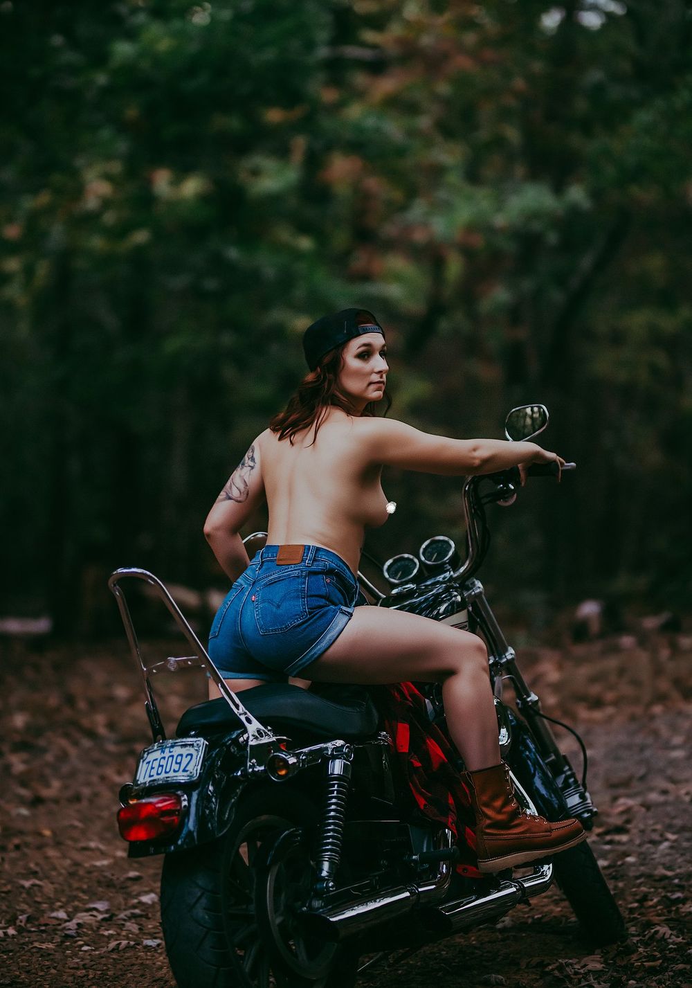 Artistic motorcycle shoot in forest with vintage bike and denim styling.