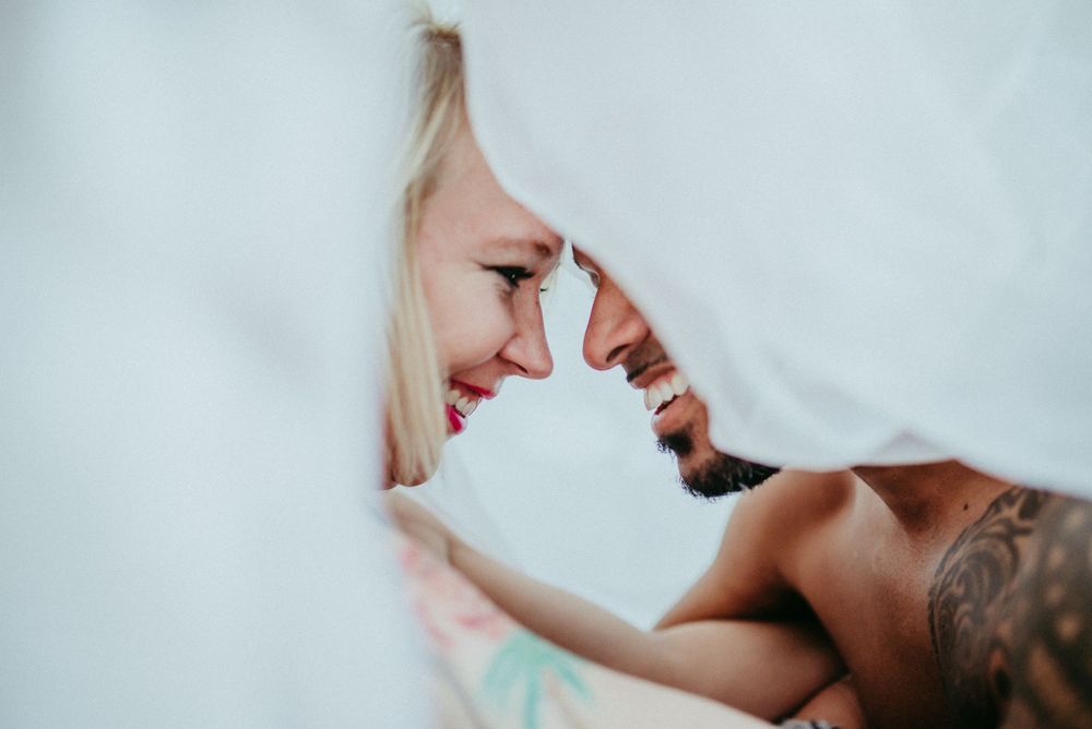 Intimate couple portrait through fabric with soft natural lighting.