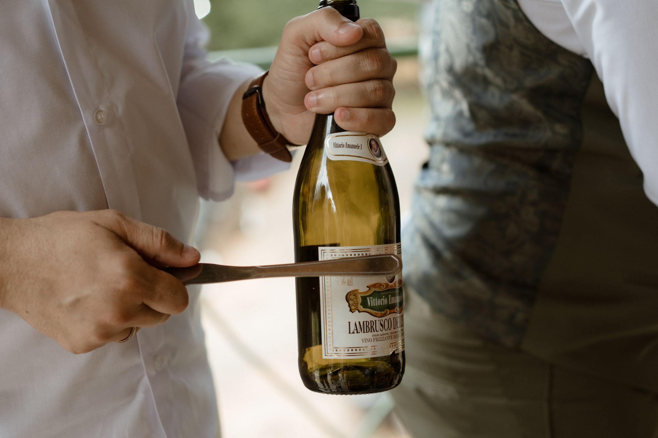 Hands hold wine bottles during wedding festivities.