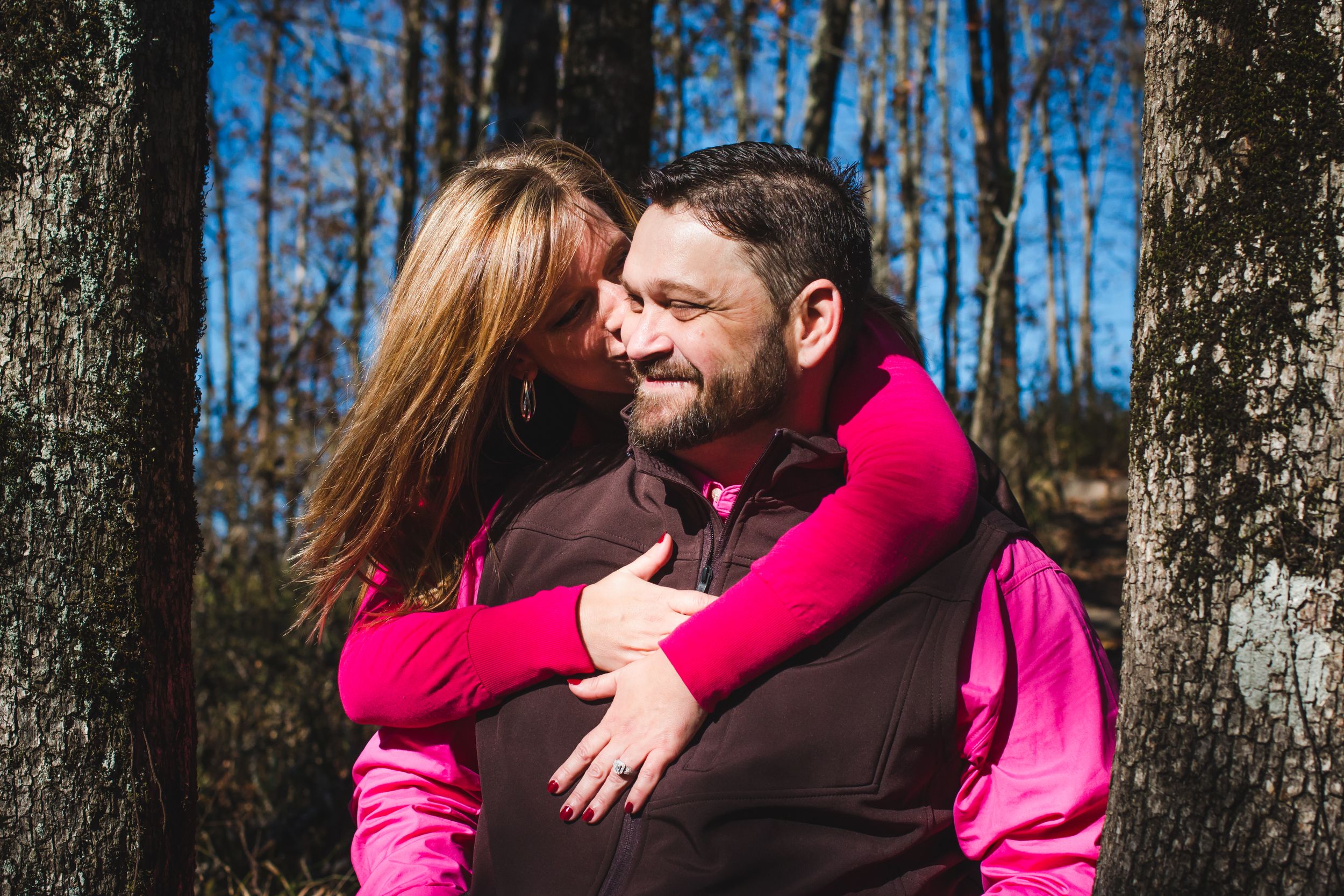 Couple sharing an intimate moment in a winter forest setting.