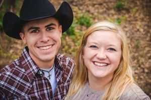 A happy couple in western attire smiling outdoors.
