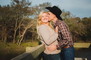 A romantic moment shared between an engaged couple on a wooden dock by a lake.