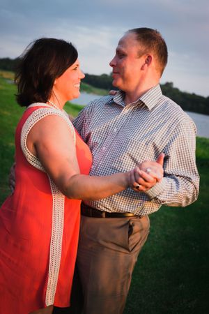 A couple shares a romantic dance outdoors in evening light.
