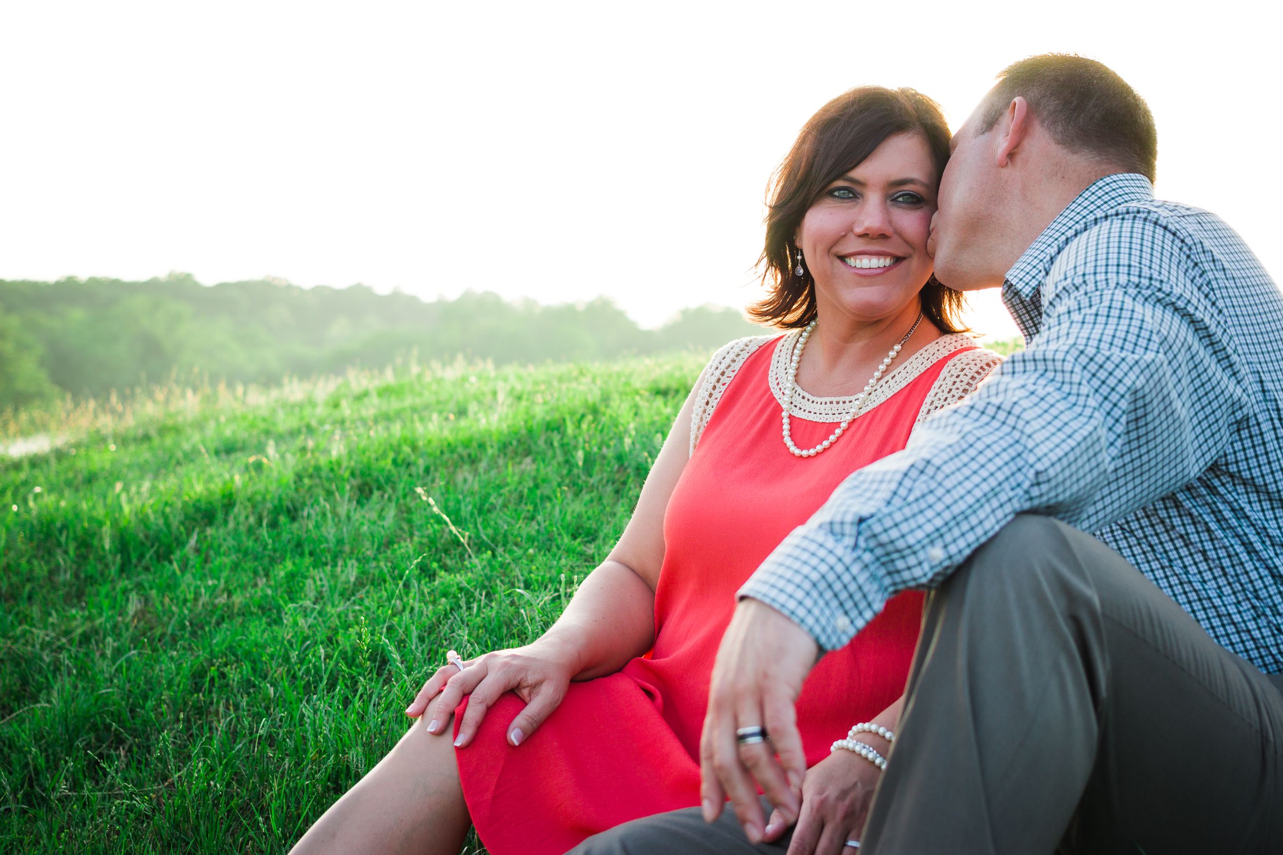 A sweet moment shared between a couple sitting in a sunlit meadow.